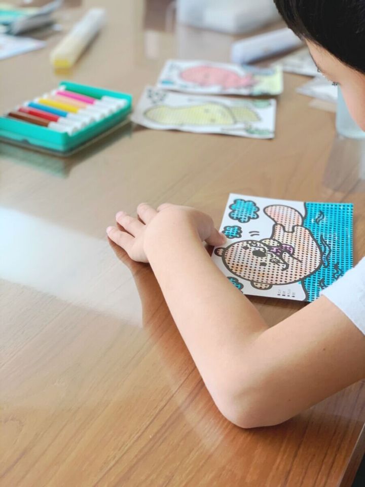 子供がテーブルでビーズアートのような作品を制作している手元
