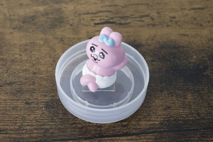 透明な蓋の中に立つピンク色の小さなウサギのマスコット