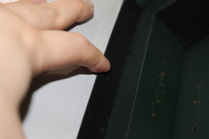 ドア枠に黒い面ファスナーを貼り付けている手元のクローズアップ