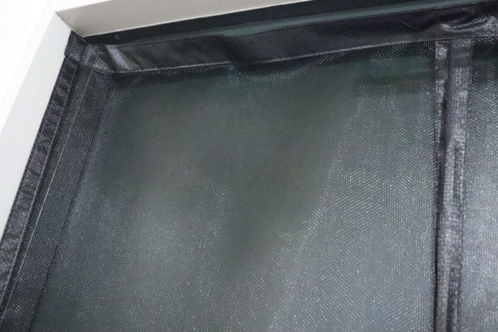 ドア枠に取り付けられたマグネット式網戸の上部が写っている