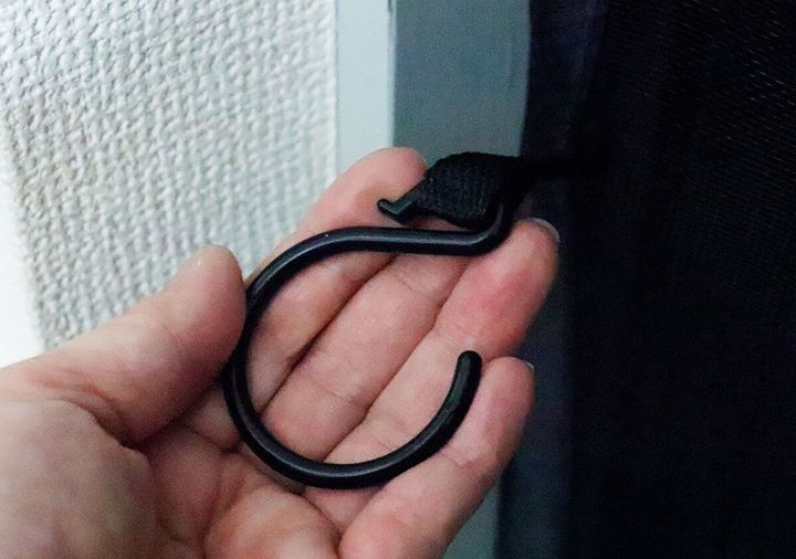 網戸を固定するための黒いフックを手に持っている様子
