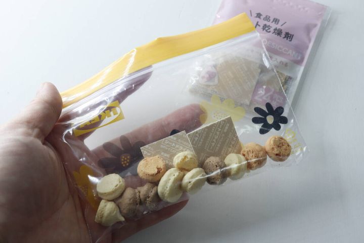 マカロンとシート乾燥剤が入ったジップバッグを手に持っている様子