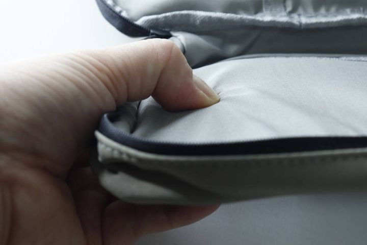 指でポーチのクッション性のある素材を押して確認している様子