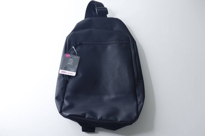 白い背景に置かれた黒い斜めかけバッグと商品タグ