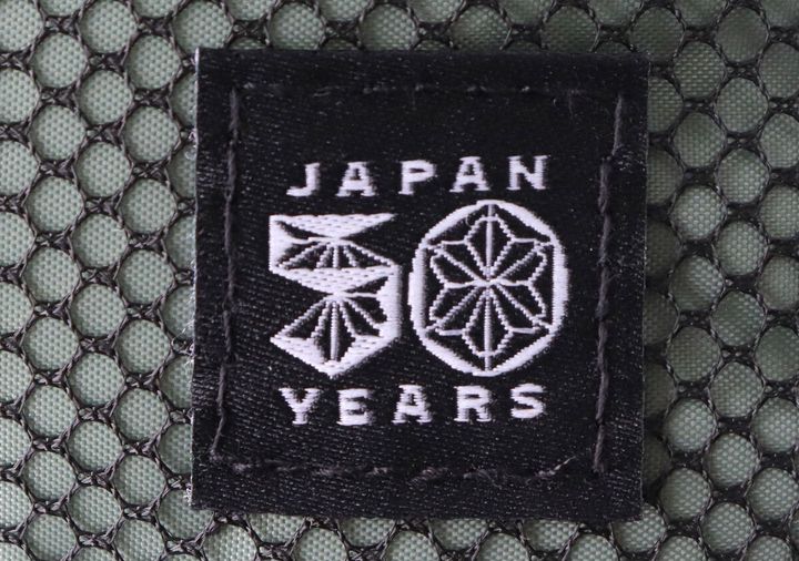 コールマン50周年記念ロゴが刺繍された黒いタグのクローズアップ