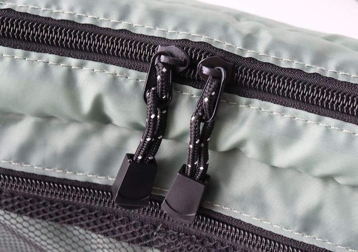 カーキ色のショルダーバッグのメイン収納部のダブルファスナーがクローズアップされている