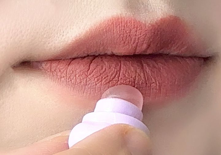 女性の唇に、くまちゃん形のミニリップブラシでリップを塗っているクローズアップ