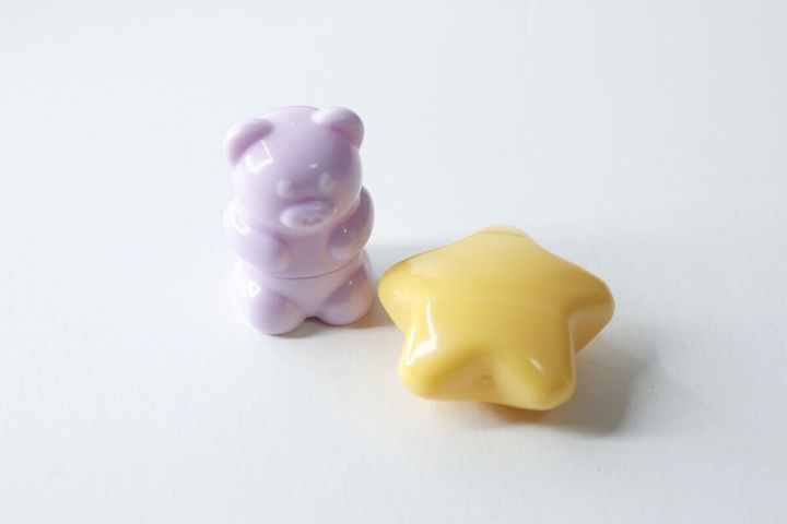 白い背景に置かれた、くまちゃん形と星形のミニリップブラシ（キャップ付き）