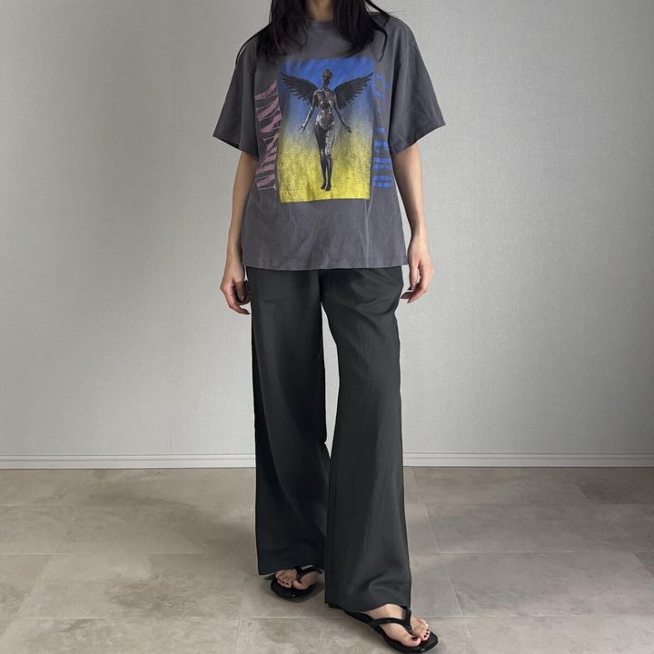 グラフィックTシャツとダークグリーンのリネンパンツを着用した女性