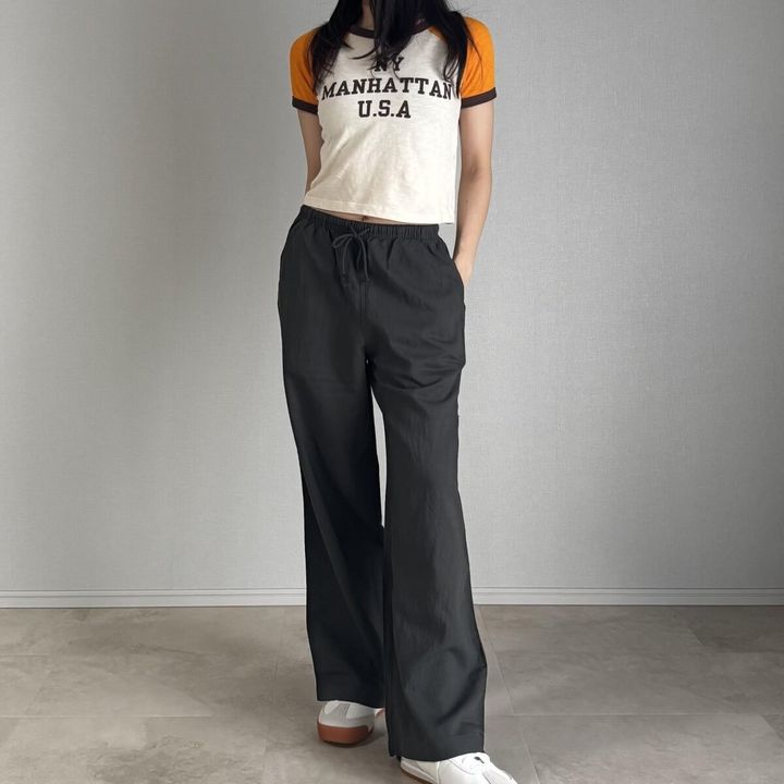 ロゴ入りミニTシャツとダークグリーンのリネンパンツを着用した女性