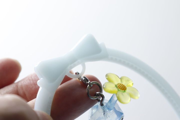 チャームスタンドの輪にカニカンでチャームを取り付ける手元