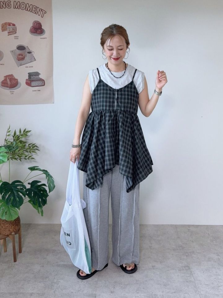 白Tシャツにチェック柄アシンメトリーキャミとグレーのスウェットパンツの女性