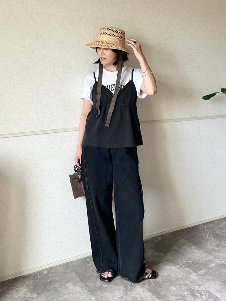 ロゴTシャツに黒キャミとワイドデニム、麦わら帽子を被った女性