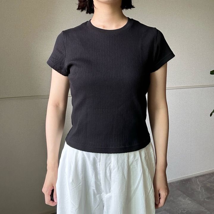 黒いリブミニTシャツと白いワイドパンツを着用した女性の全身