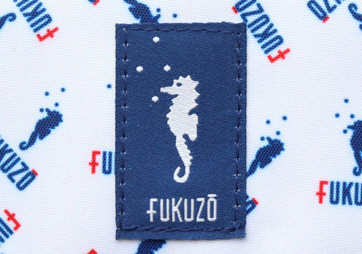 FUKUZOのロゴとタツノオトシゴが刺繍されたネイビーのタグ