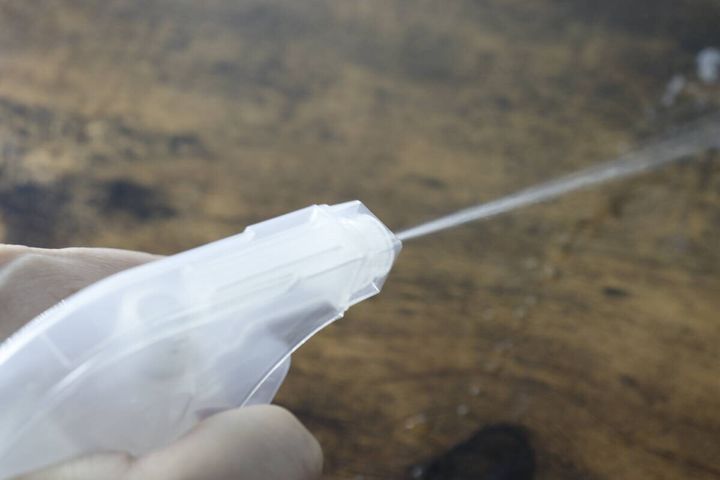 スプレー容器から直線状に液体が勢いよく噴射されている