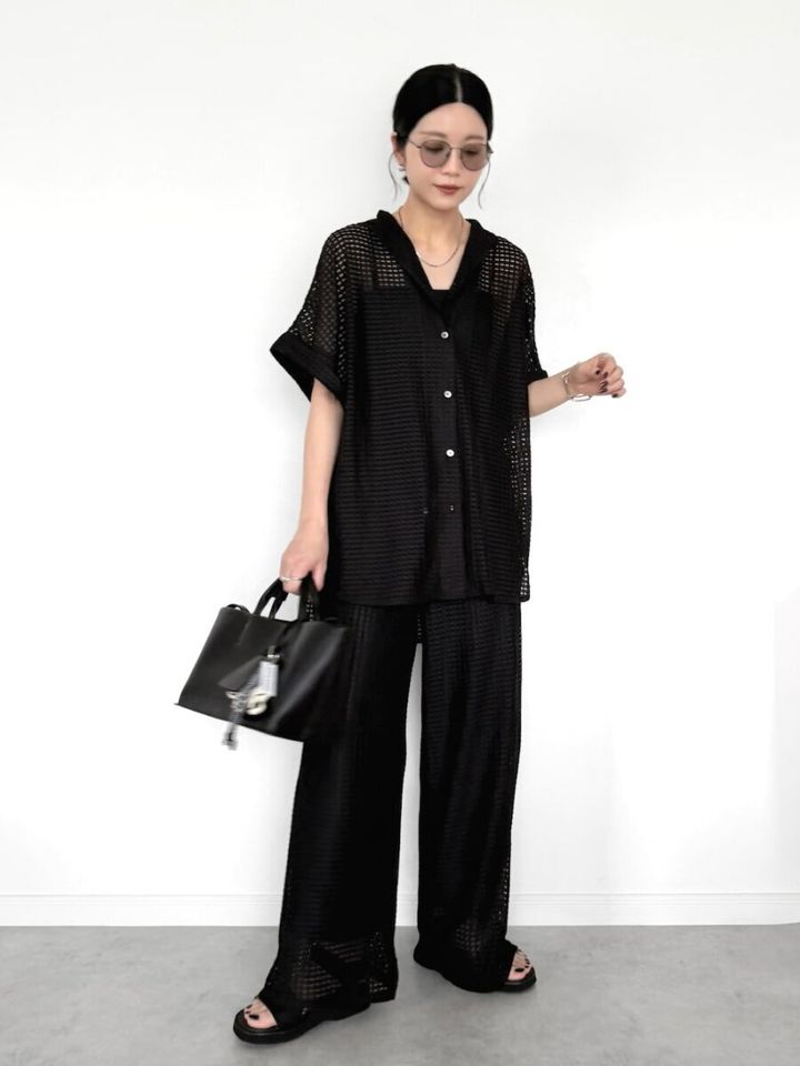 メッシュ素材の黒シアーシャツと黒ワイドパンツのオールブラックコーデの女性