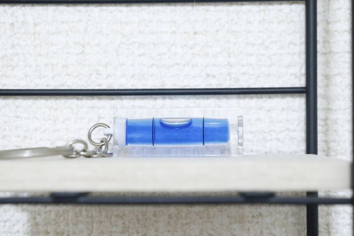 白い棚の縁に置かれたキーホルダー水平器