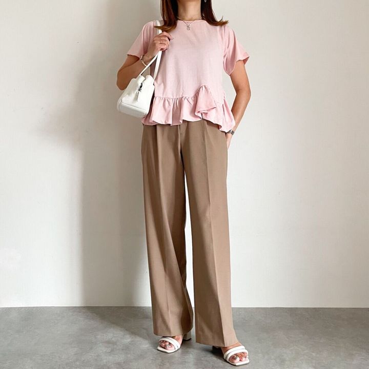 ピンクのペプラムトップスとベージュワイドパンツ、白いサンダルのきれいめコーデ。