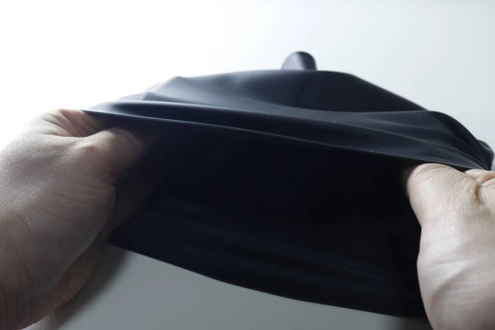 両手で黒いシリコーン水泳帽を広げている