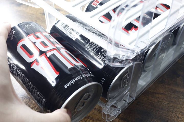 缶ボトルホルダーから黒い缶ドリンクを取り出す手元