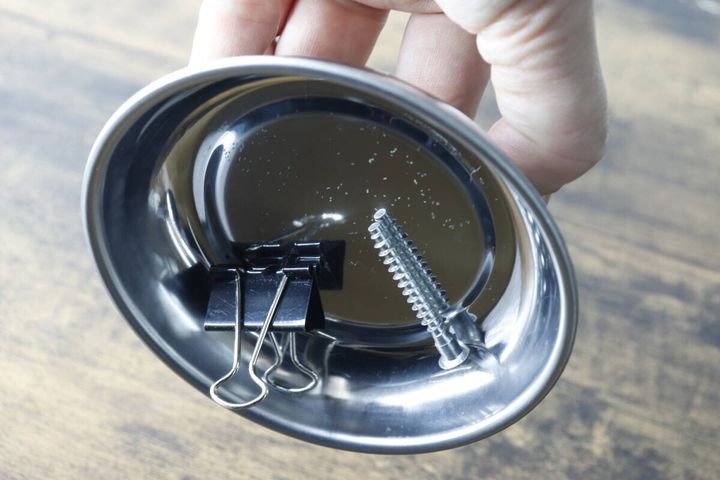 女性がマグネット付パーツトレーを傾けてもネジとクリップが落ちない様子