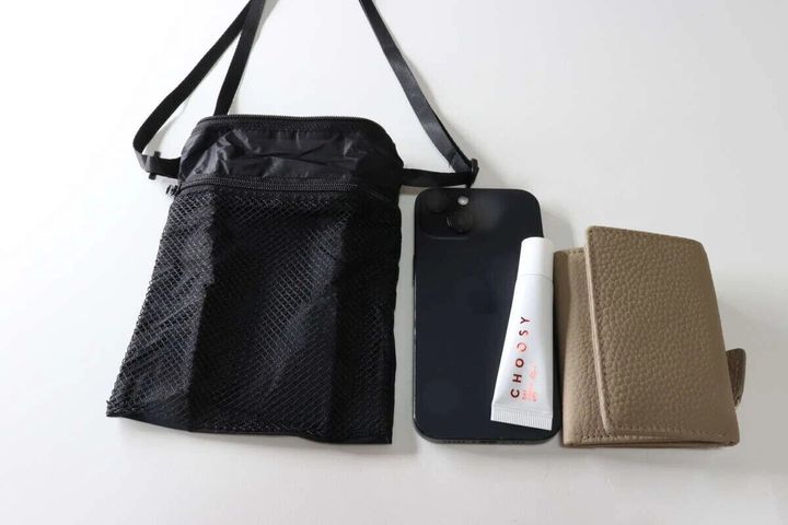 黒いトラベルショルダーバッグと、スマホ、リップ、ミニ財布が並べられている