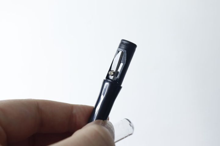 指で持った黒いペンシルシャープナー本体と透明なフタ