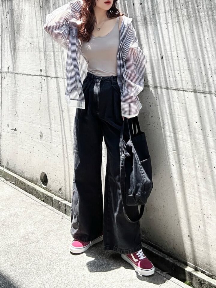 ベージュタンクトップとギンガムチェックシアーシャツ、黒デニムの女性