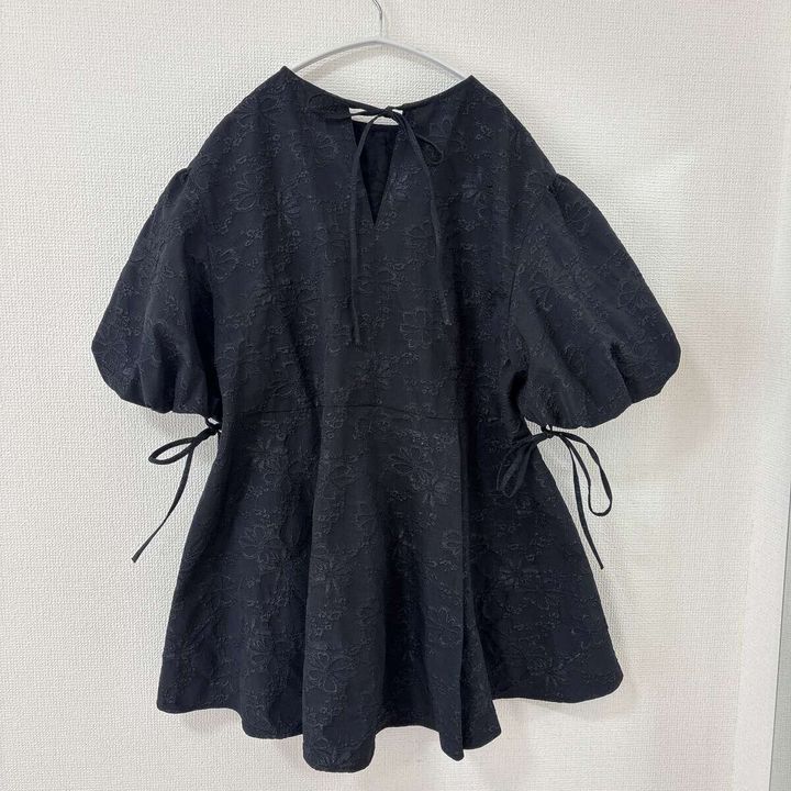 黒いバルーンスリーブチュニックの後ろ姿がハンガーにかかっている