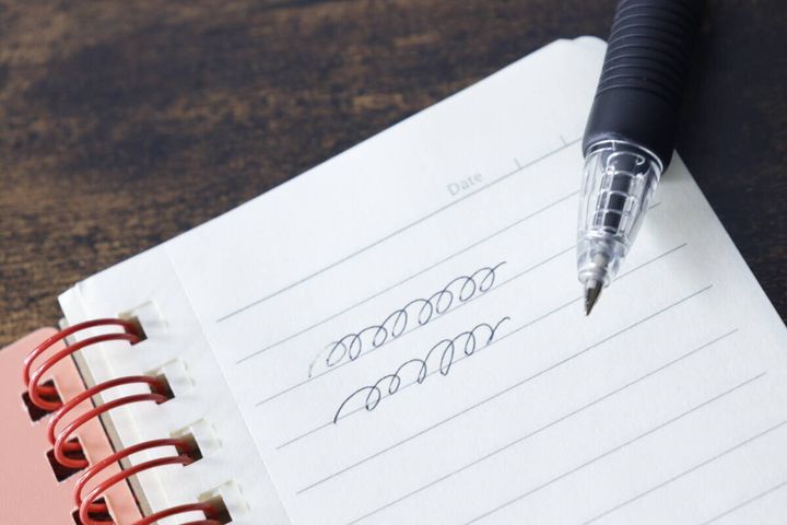 ノートにショートボールペンで試し書きをしている様子