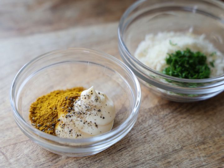 2つの透明なガラスボウル。手前にはマヨネーズ、カレー粉、ブラックペッパー、奥にはパン粉、粉チーズ、刻みパセリが入っている