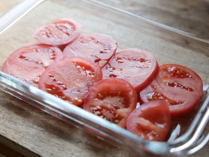 ガラス製の耐熱容器の底に、7～8mmの厚さにスライスされたトマトが並べられている