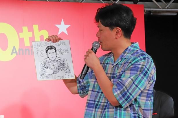 贈られた似顔絵を眺める阪本さん。ステージには「すげえ！」「かっこいい」と声が飛び交っていた