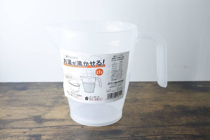 商品パッケージが貼られた透明な計量カップが木目のテーブルに置かれている