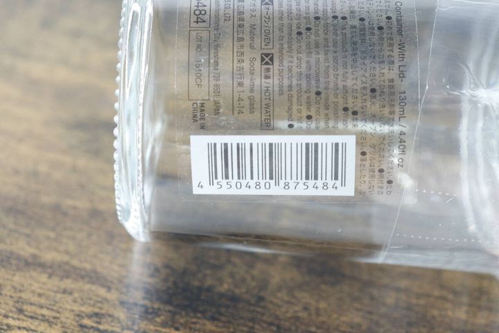 ガラス容器に貼られた商品情報シールの拡大。JANコードや使用上の注意が読み取れる。