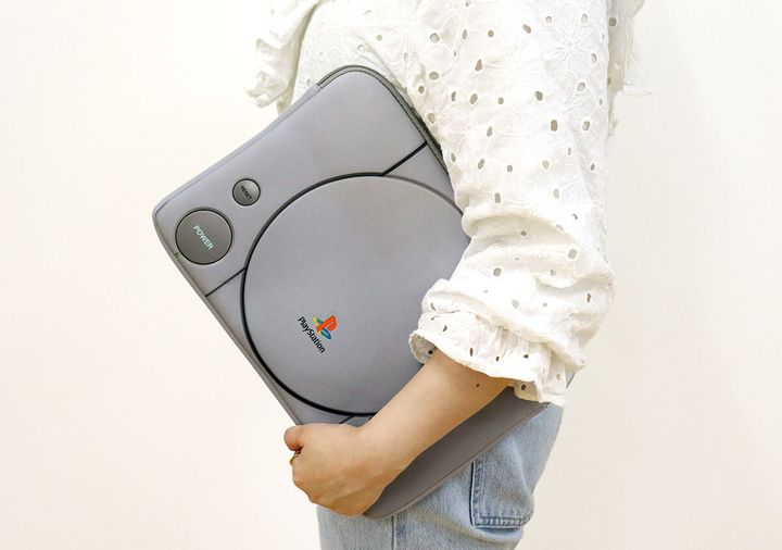 白い服の女性が初代プレステ型ケースを脇に抱えて歩く