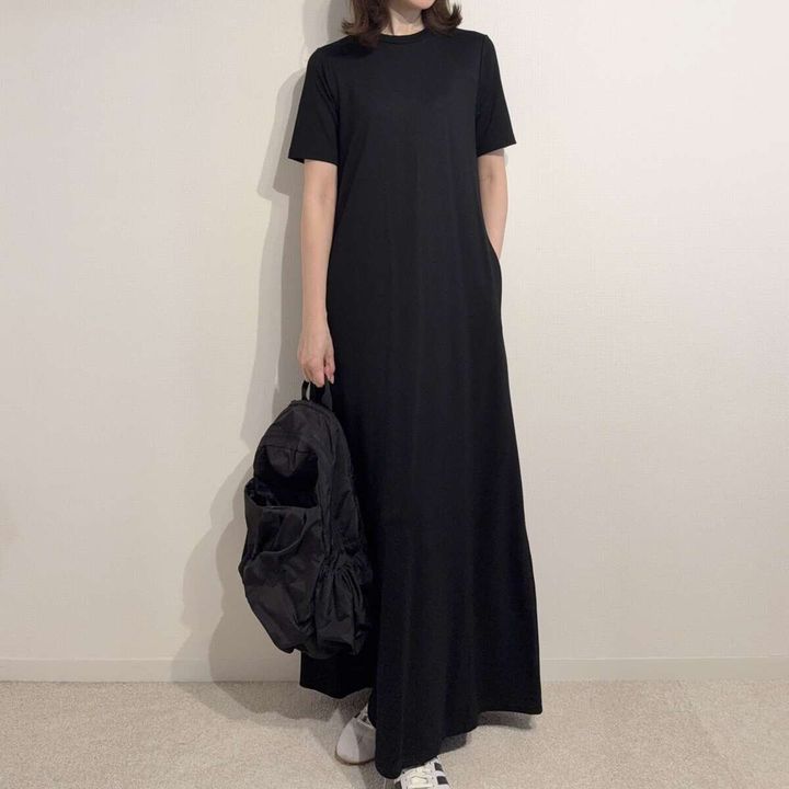 黒いワンピースに黒いリュックとスニーカーを合わせた女性の全身