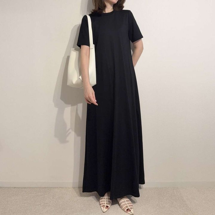 黒いワンピースに白いバッグとサンダルを合わせた女性の全身