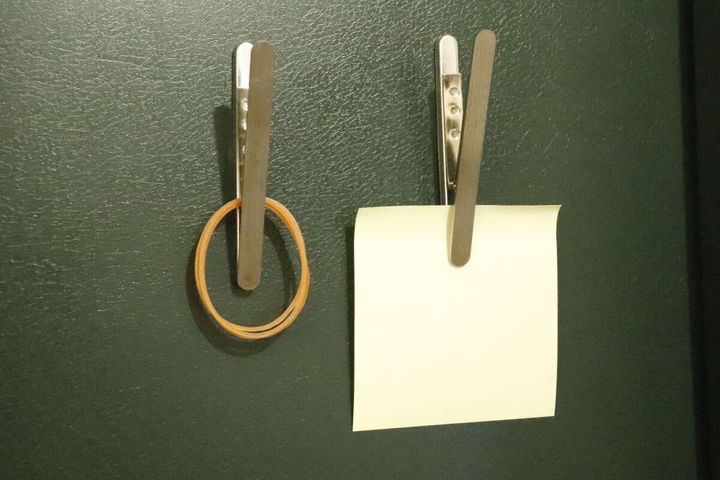 冷蔵庫に貼られたマグネットクリップで輪ゴムとメモを挟んでいる