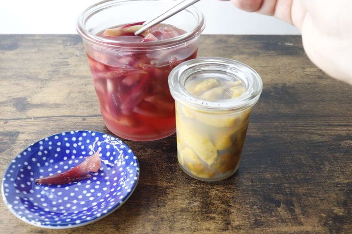 青い水玉模様の豆皿に赤いピクルスが盛られ、奥に瓶詰めのピクルスが2つ置かれている