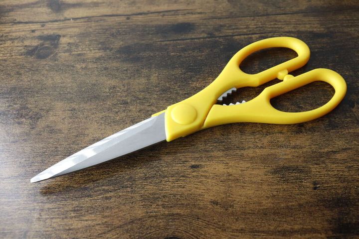 木目調のテーブルに置かれた黄色いダイソーキッチンハサミ