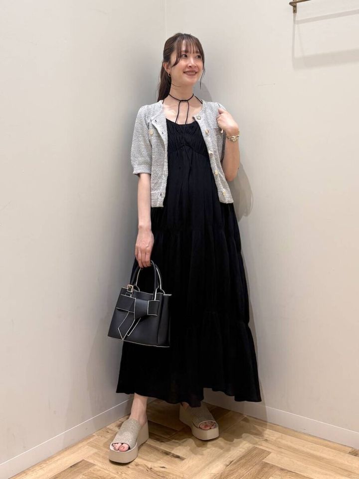 黒キャミワンピにツイード半袖カーデを羽織りハンドバッグを持つ女性