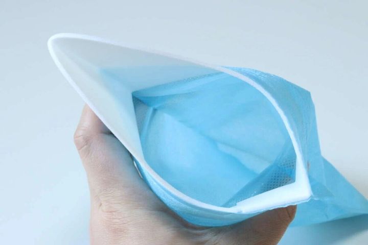 青い携帯できるトイレの開口部を広げて持っている手