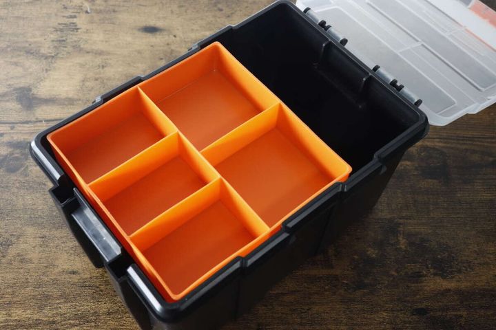 蓋を開けた黒い工具箱の中に、仕切り付きのオレンジ色のトレーが見える