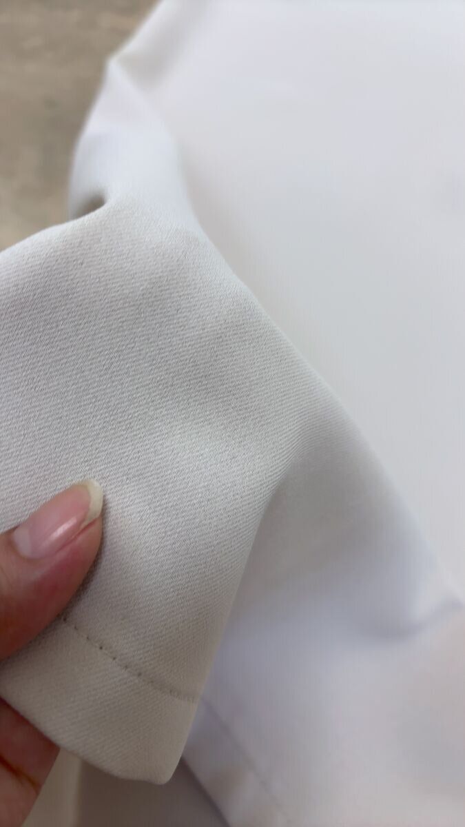 ワイドパンツの生地を指でつまんで質感を見せている