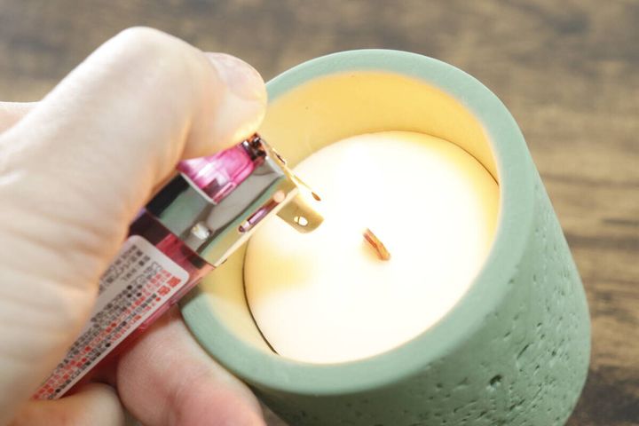 ピンク色のライターでキャンドルの木芯に火を灯している瞬間