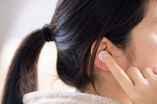 耳にワイヤレスイヤホンを装着する女性の横顔