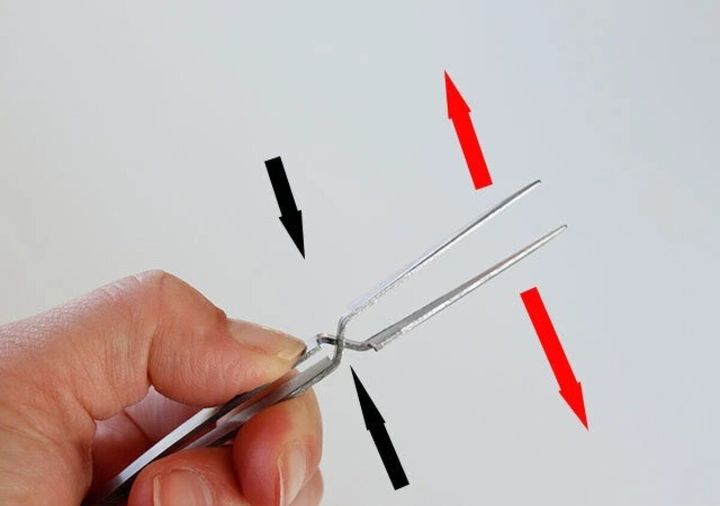 指で逆作用ピンセットを握り、動作を説明する矢印が描かれている