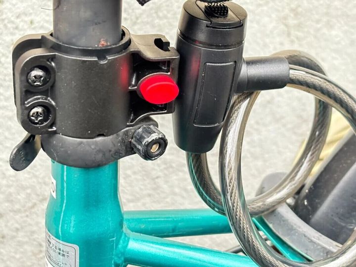 緑色の自転車のサドル下支柱にワイヤーロックのブラケットが取り付けられている様子